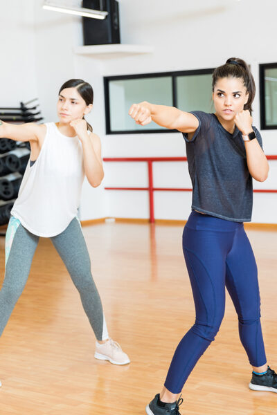 Determined women in sportswear punching the air in gym