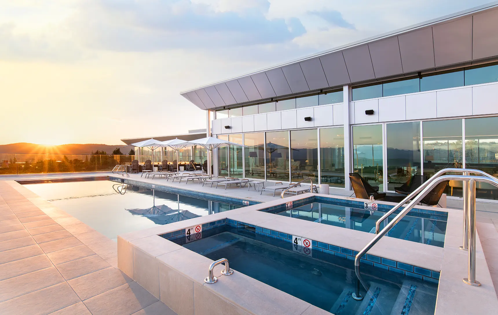 The pool at the Sky House in Promontory Club as the sun sets over the Wasatch Mountains in the background.